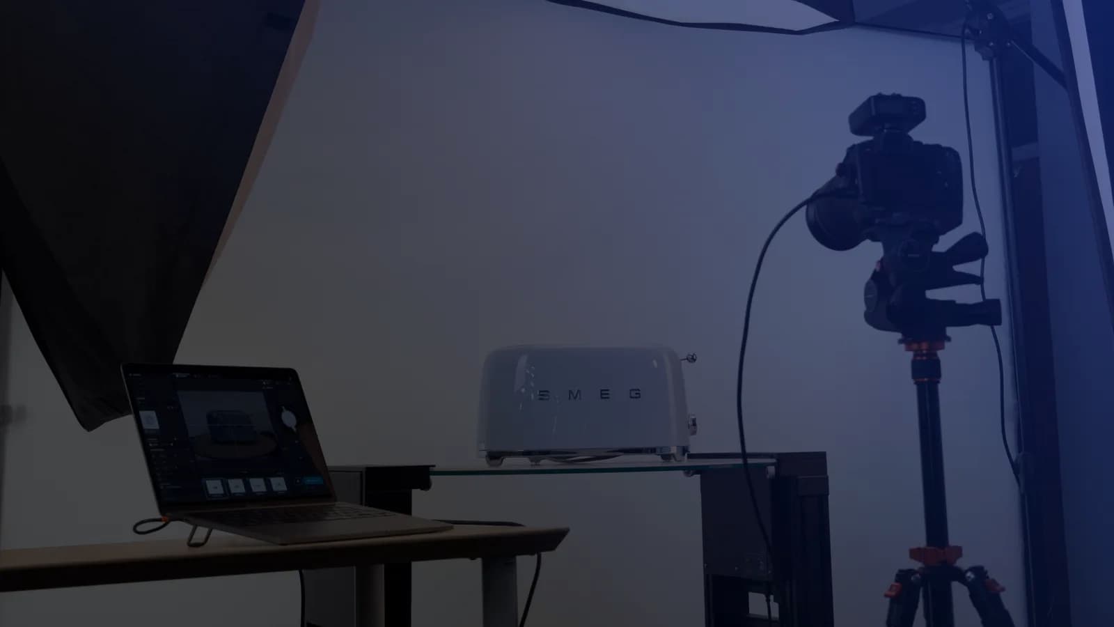 Tethering-Setup in der Produktfotografie - ein Laptop mit Aufnahmesoftware neben einer Kamera auf dem Stativ und einem Produkt auf einer Glasplatte
