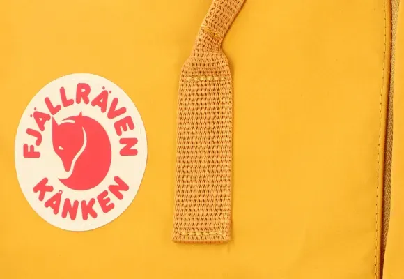 Nahaufnahme des Logos und Trageriemens eines gelben Rucksacks