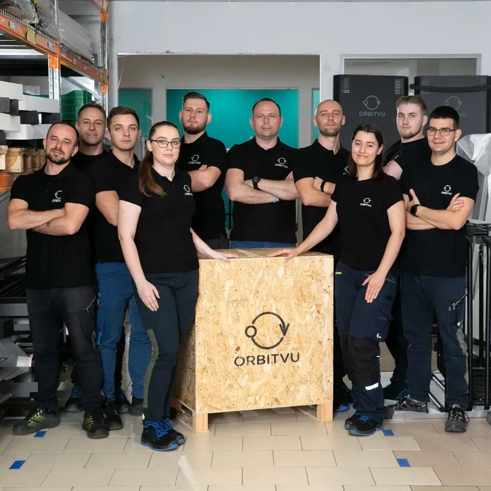 Produktions- und Logistikteam von Orbitvu posiert mit gebrandeter Holzkiste