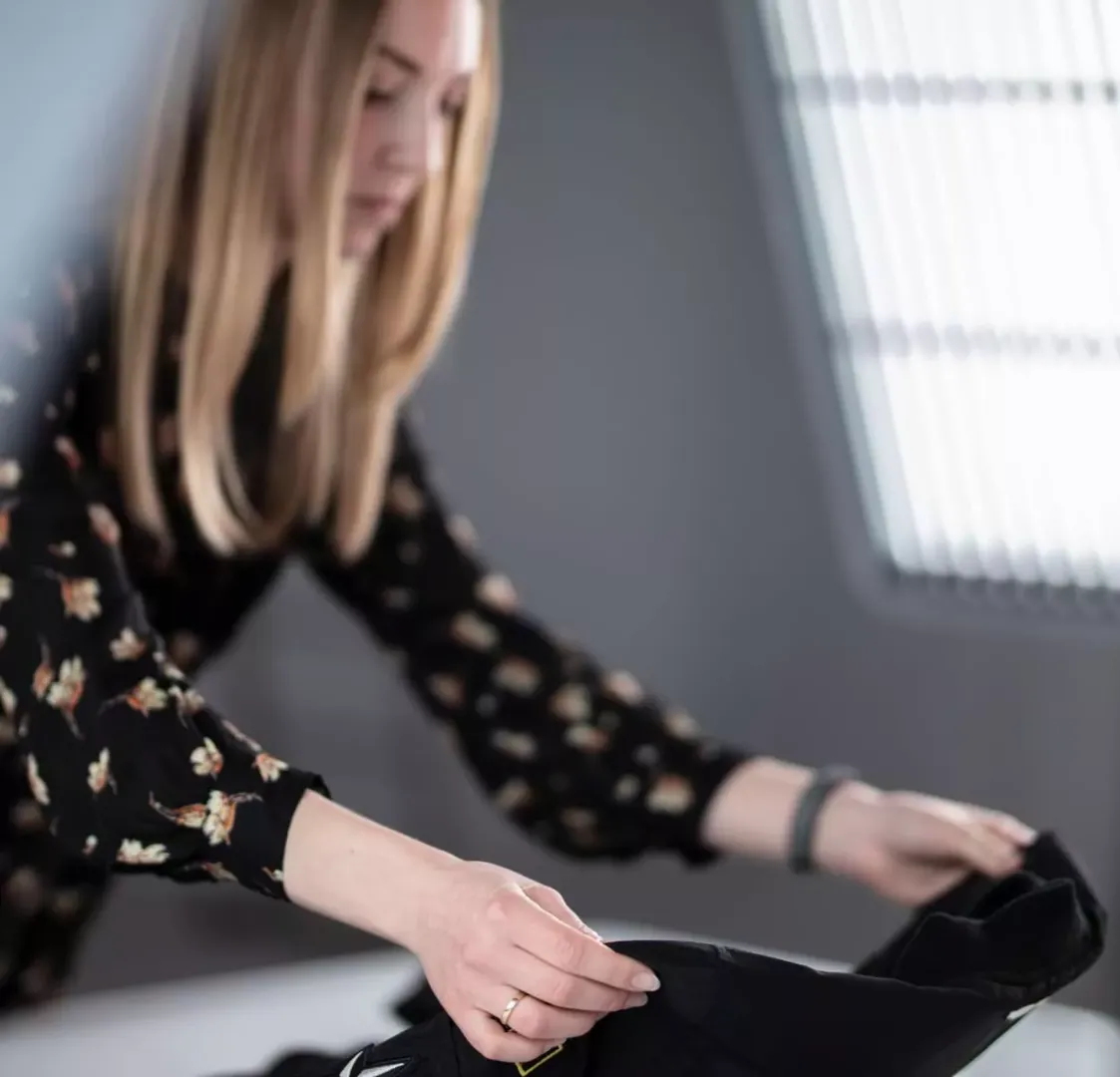Produktstylist richtet ein schwarzes Kleidungsstück für ein Flat-Lay-Shooting aus