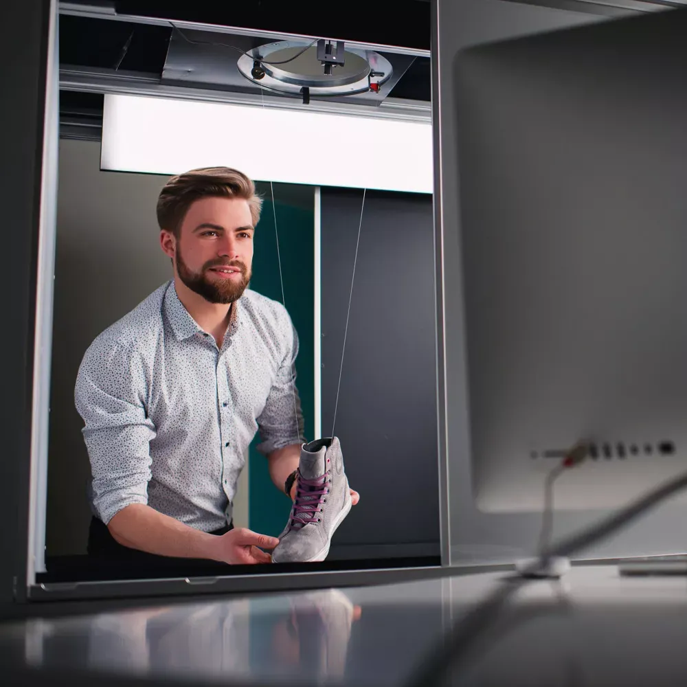 Mann bereitet ein Produkt für professionelle Schuhfotografie vor