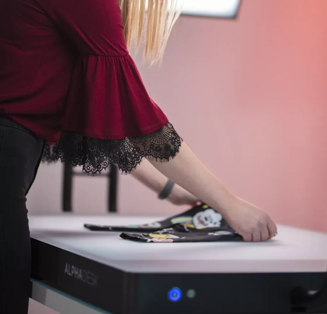 Frau faltet Kinderkleidung auf einem weißen Tisch mit dem Alphadesk